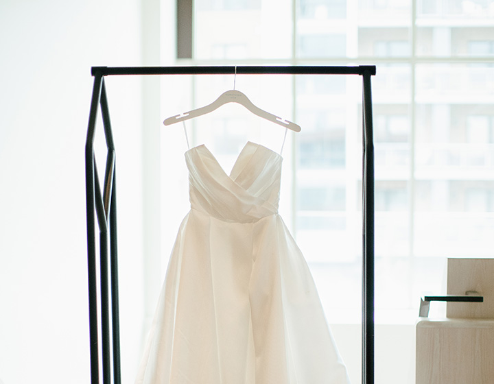 Wedding dress hangs in front of guestroom window at Kimpton Claret Hotel